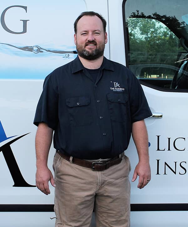Plumbing Authority crew member standing in front of a work truck